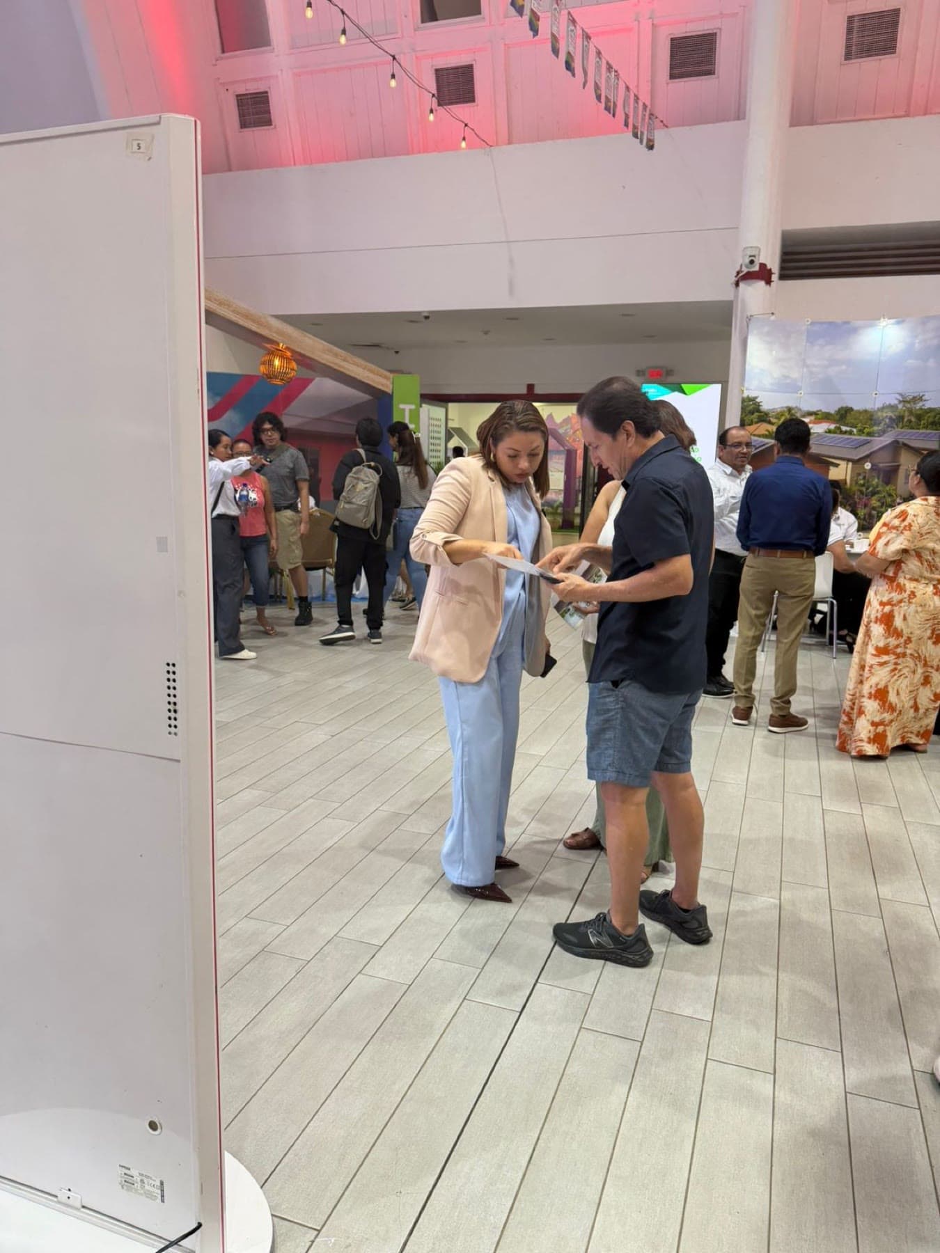 Una asesora de Bhumi repasa un documento con un visitante en el pasillo de la feria