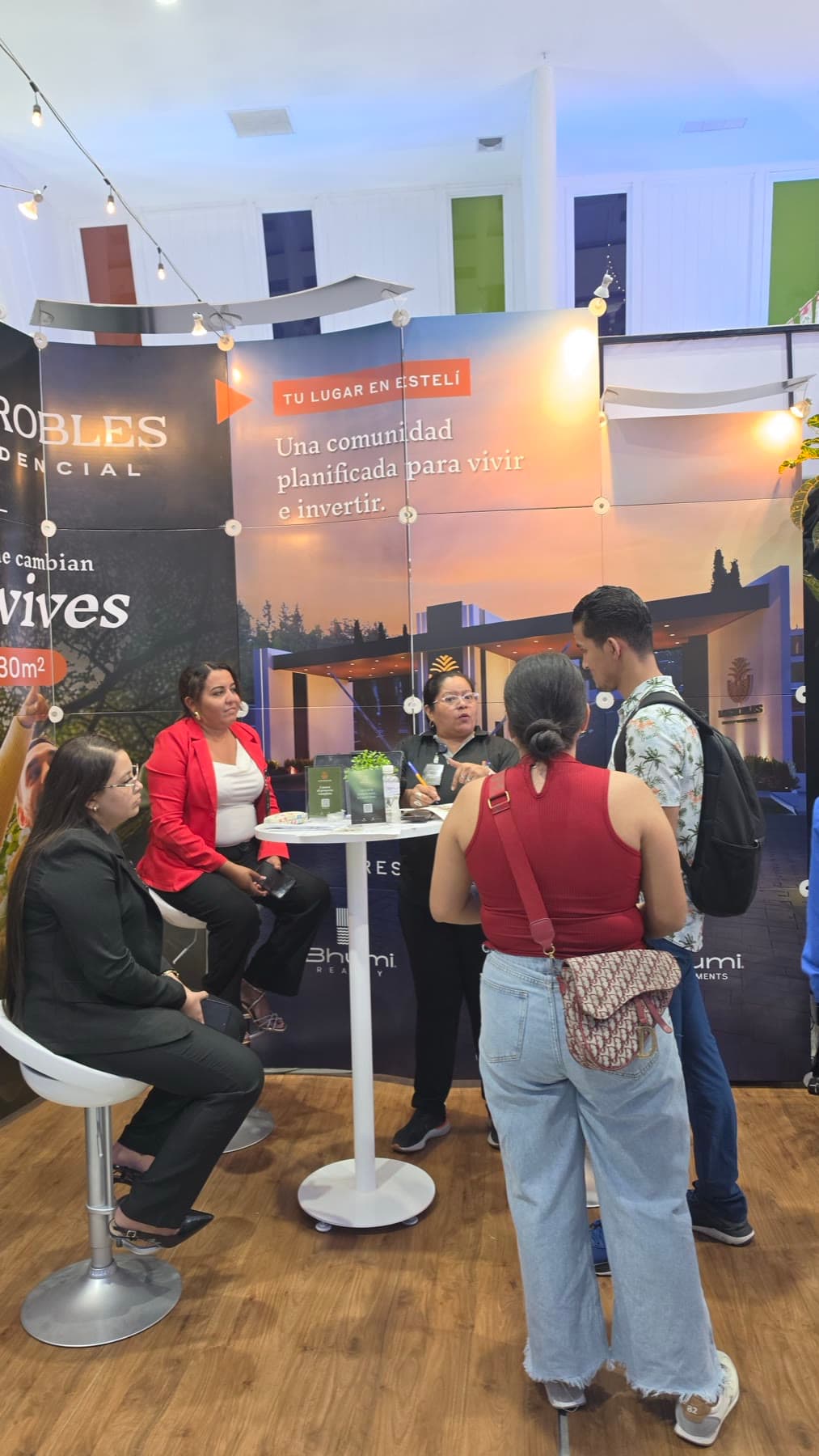 Visitantes conversando alrededor de la mesa del stand de Los Robles Residencial