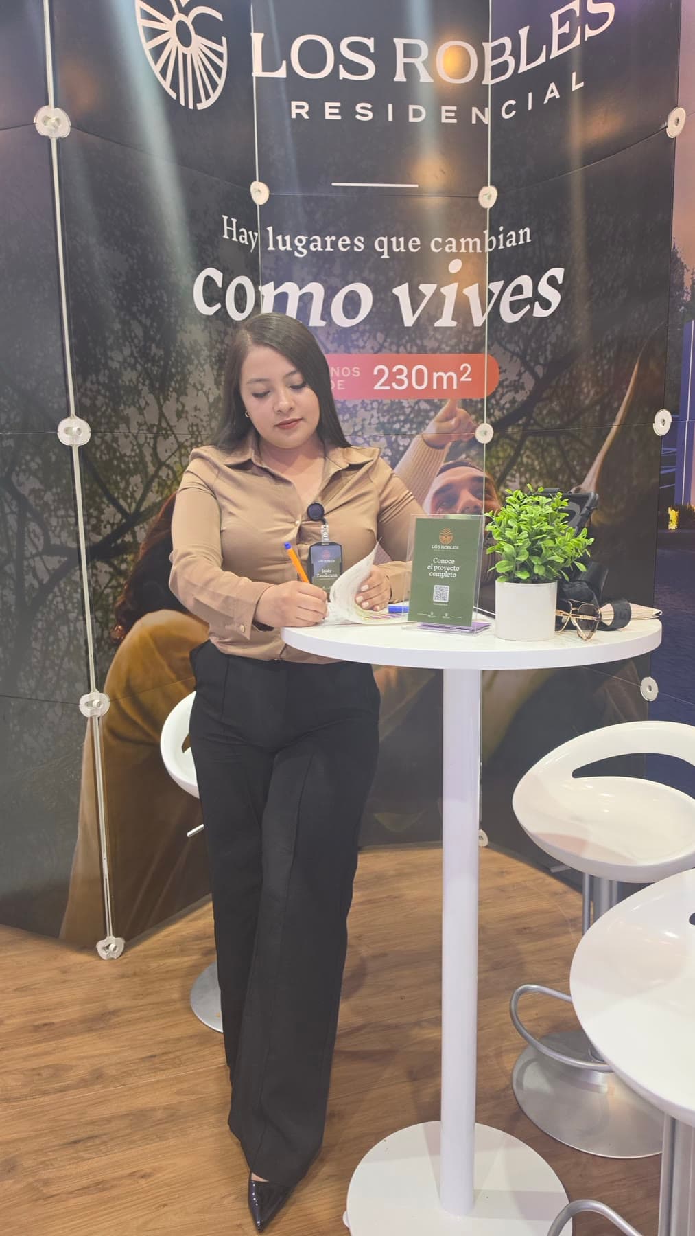 Una asesora toma notas en la mesa del stand de Los Robles Residencial