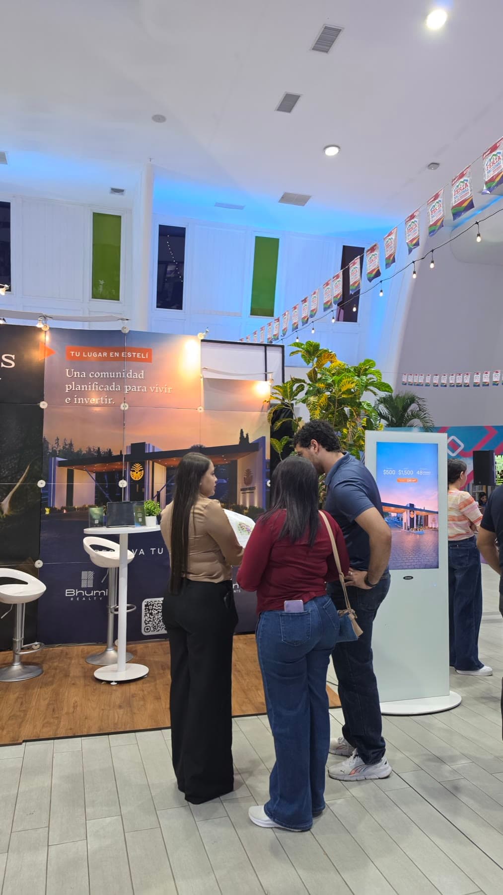Visitantes frente a la pantalla del stand con los planes de pago del proyecto