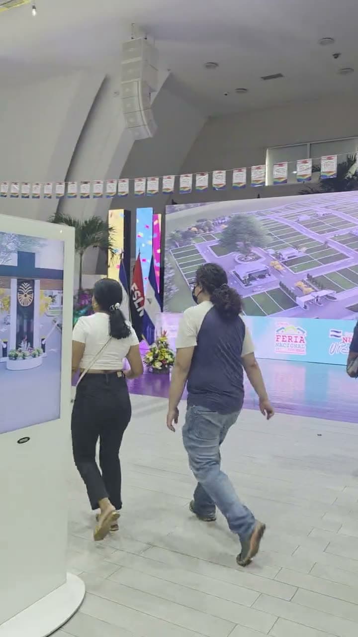Visitantes recorriendo la feria frente a la maqueta digital de una urbanización